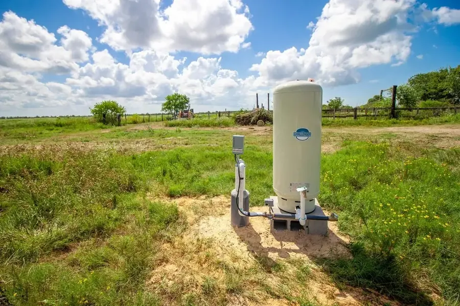A conventional water well system with a large freestanding pressure tank installed in a Texas pasture